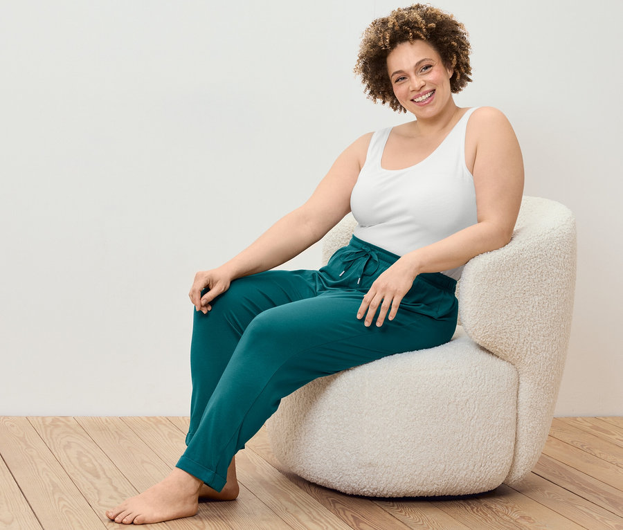 Kadın koltukta oturuyor, üzerinde 2 Adet Atlet ve Pijama Altı var.