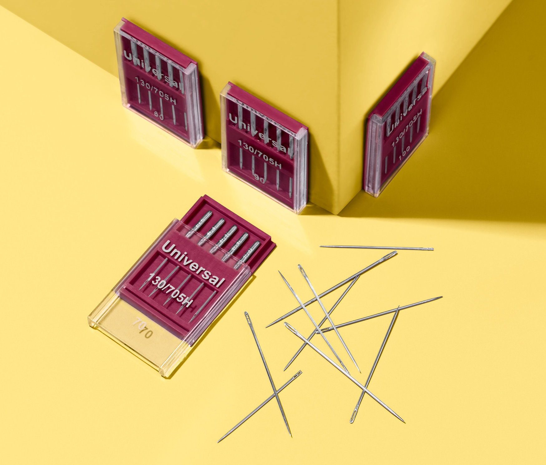 Sarı bir arka plan üzerinde dört adet Makine ve Dikiş İğnesi Seti bulunmaktadır.