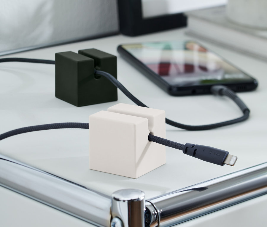 Bir Ladekabel-Organizer, 2'li Set, şarj kablolarını beyaz bir masa üzerinde tutuyor. Biri siyah, diğeri beyaz.