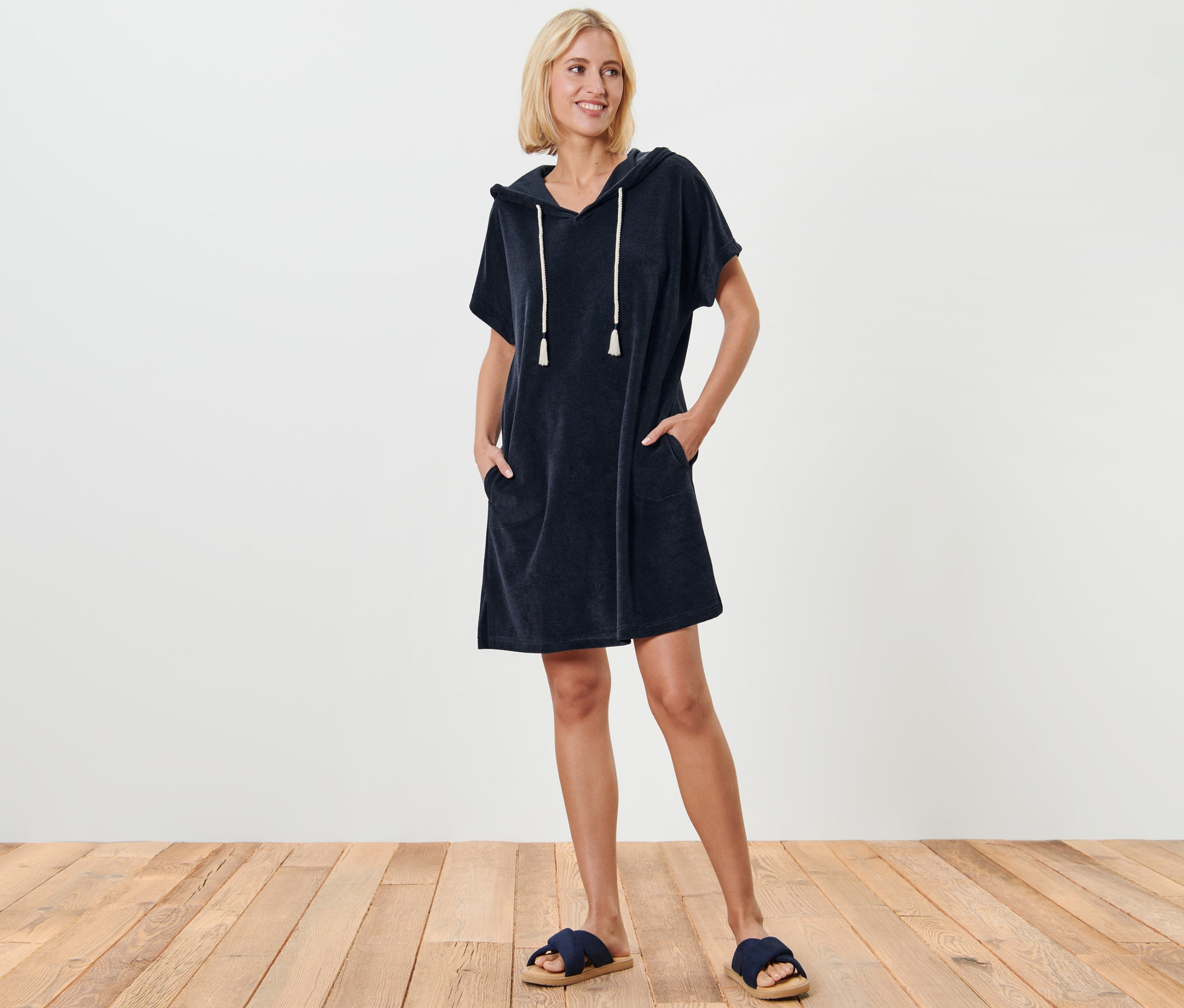 Kadın mavi havlu kumaş plaj elbisesiyle ayakta duruyor ve poz veriyor.