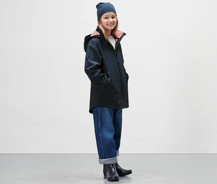 Kız çocuğu lacivert Çocuk Softshell Mont, kot pantolon ve bere giyiyor.