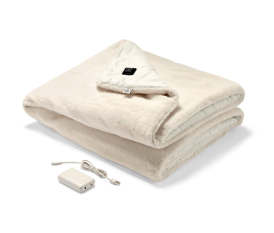 Katlanmış, krem rengi şarjlı ısıtıcı panço, kontrol paneli ve şarjı görünüyor.