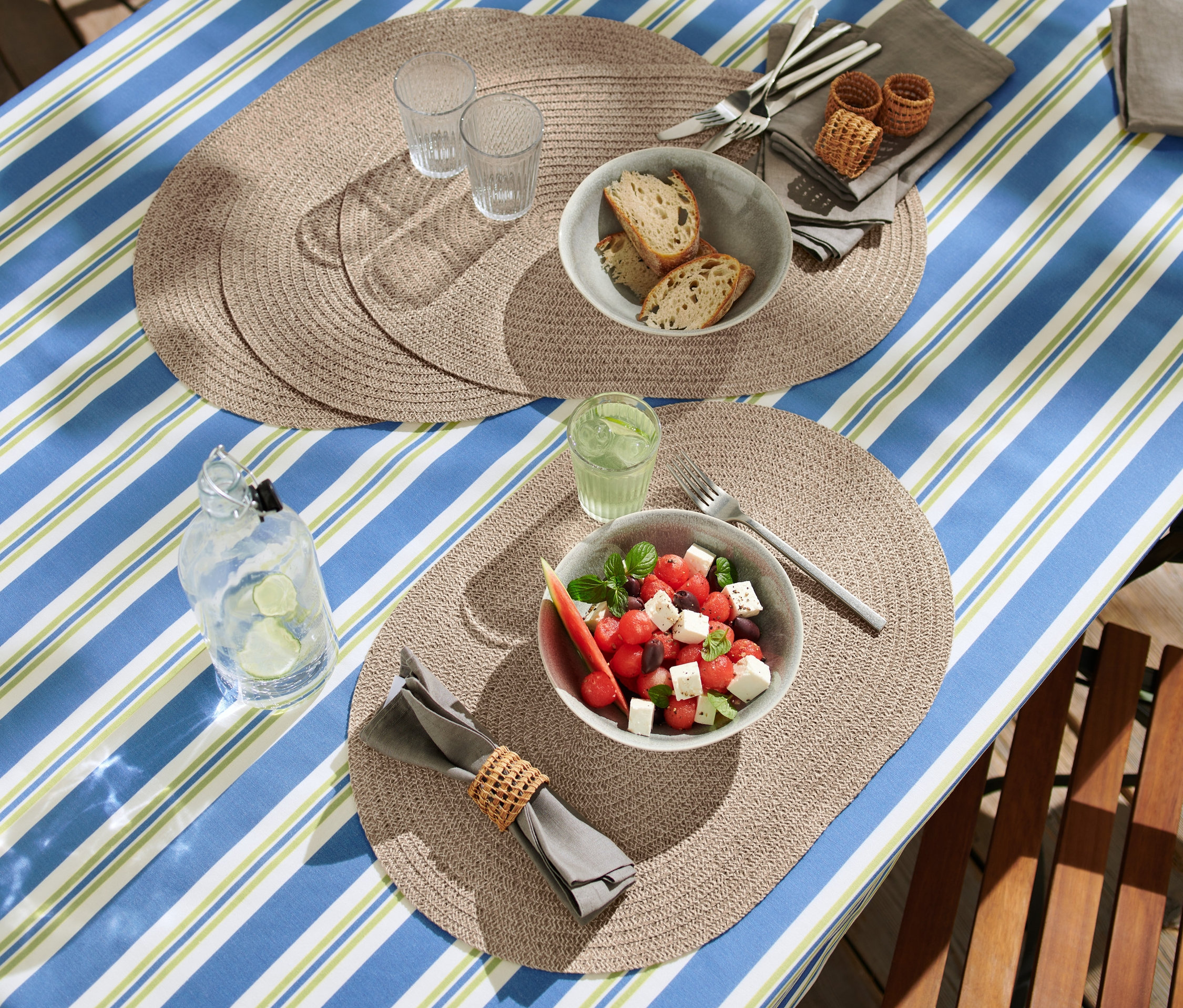 4 adet silinebilir Amerikan servis ile donatılmış masada karpuz salatası, ekmek ve içecekler bulunuyor.