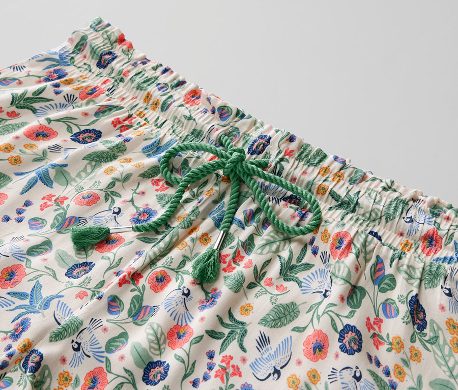 Çiçek desenli ve yeşil büzgülü bağcıklı şortlu pijama takımının yakın çekim detayı.
