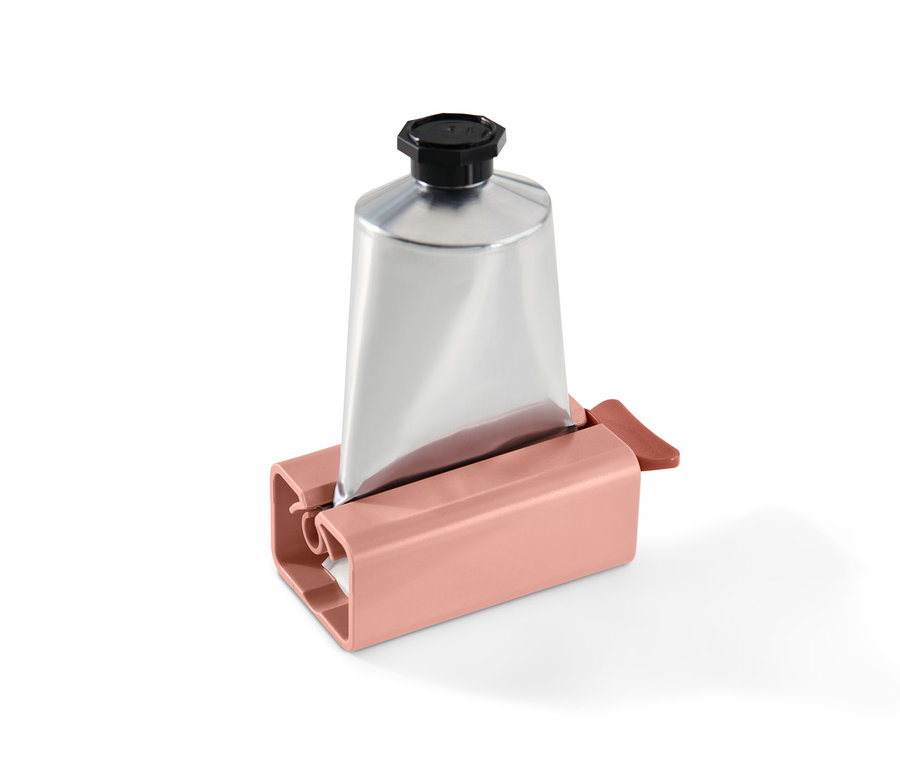 Gümüş renkli bir tüp, pembe bir tüp sıkıcının içinde duruyor.