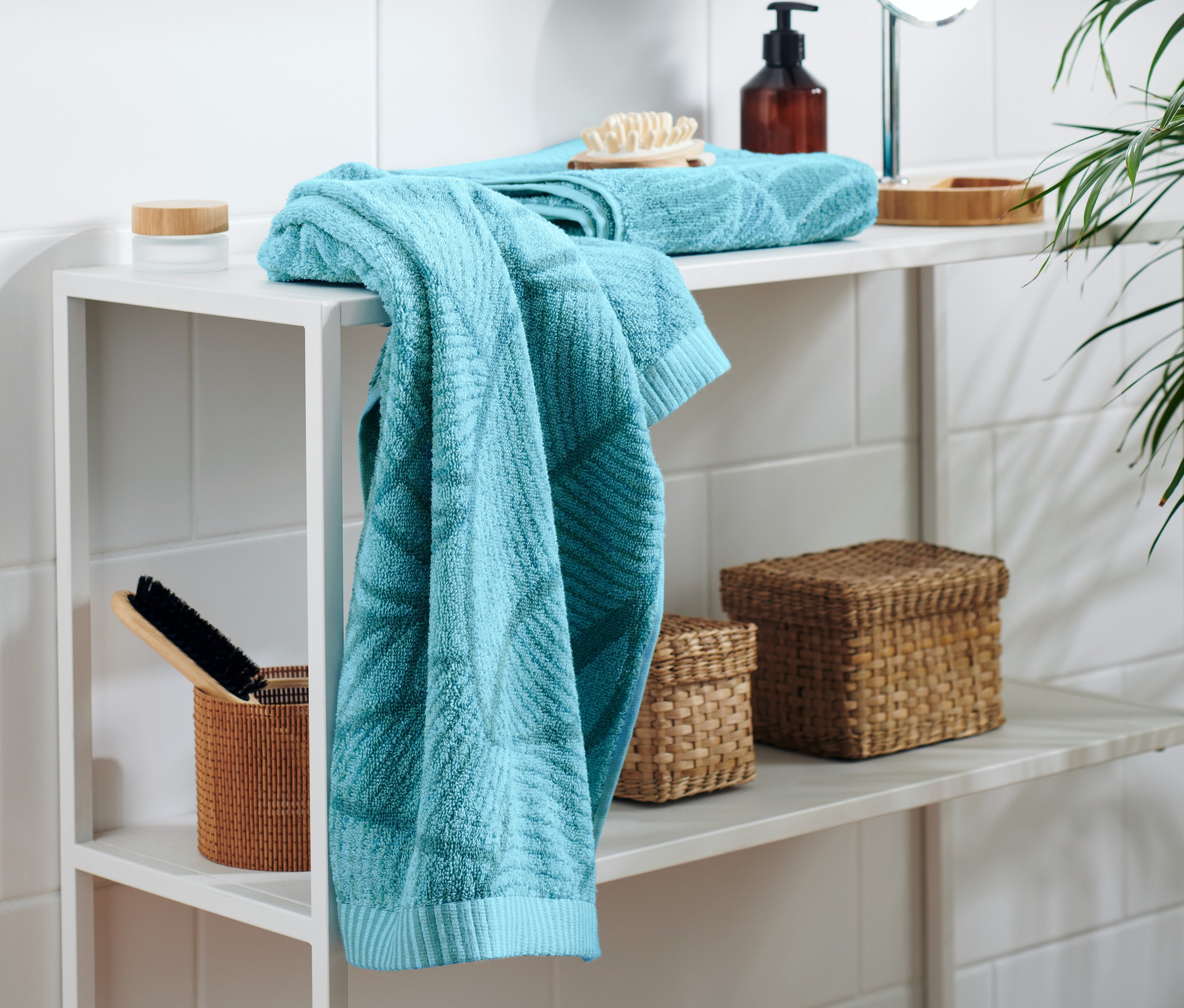 Beyaz rafta iki adet deniz mavisi jakar el havlusu duruyor.