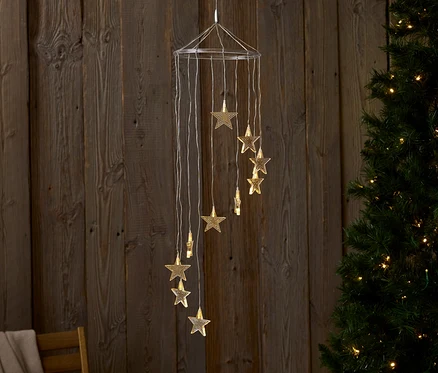 Ahşap duvar ve Noel ağacı önünde yıldız şeklinde ışıklarla asılı bir dekorasyon.