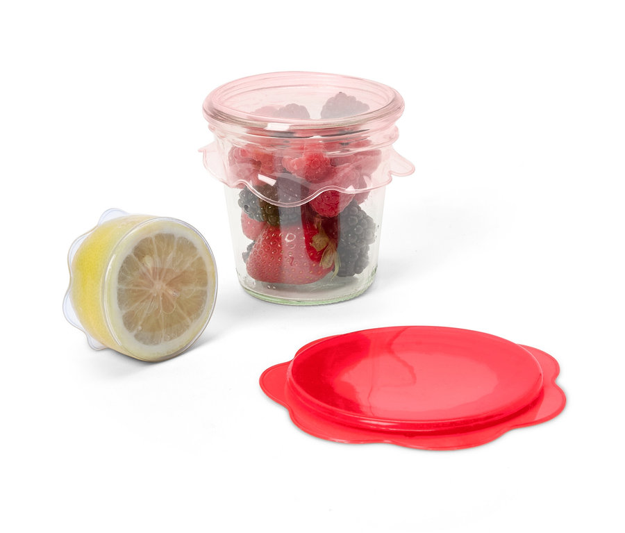 Bir kavanoz dolusu meyve 3 Silikon-Frischhaltedeckel ile kapatılmış, yanında aynı kapakla kapatılmış yarım limon ve kırmızı bir kapak.