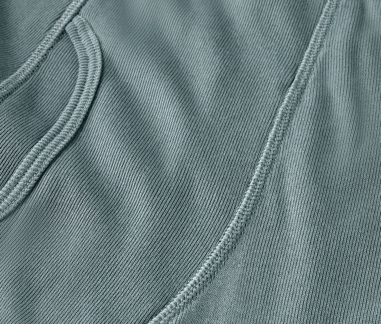 Cep ve dikiş detayları olan mavi-yeşil kumaşın yakın çekimi.