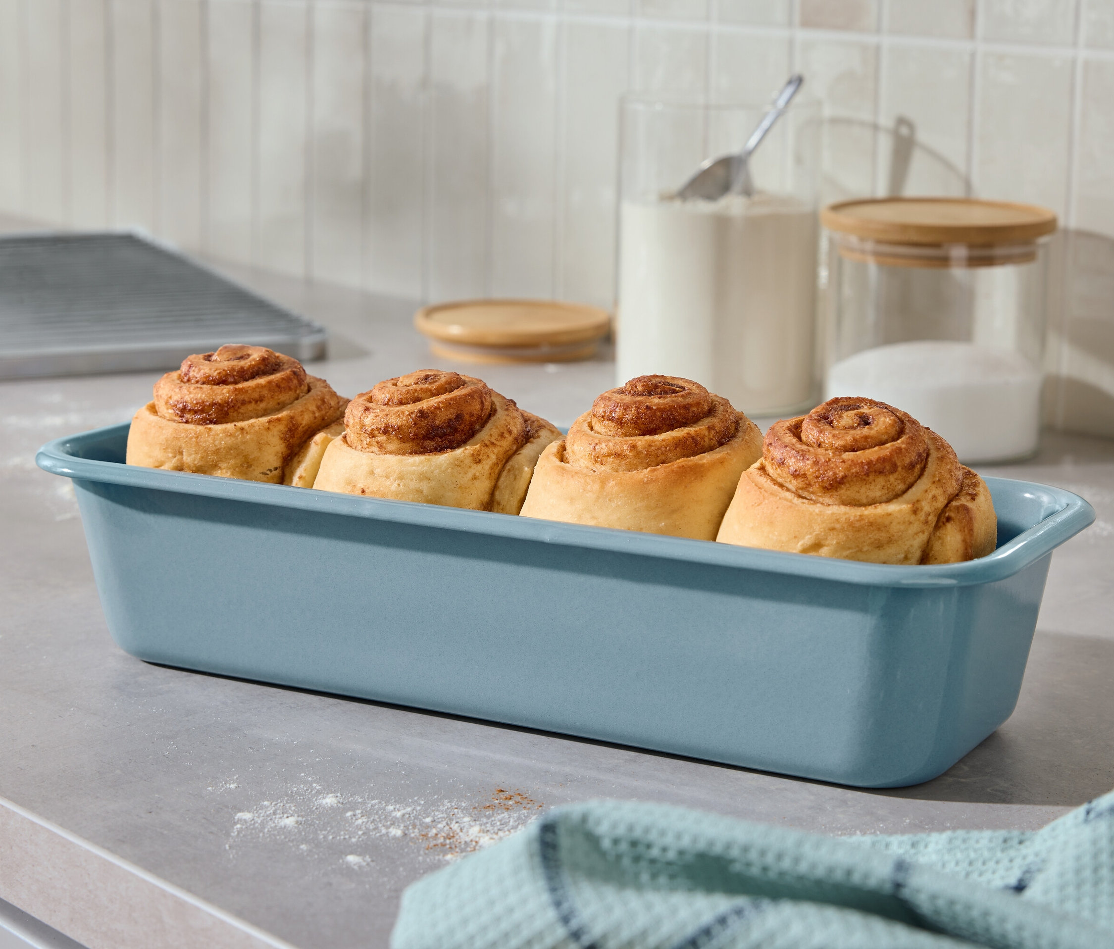 Mutfak tezgahında mavi bir fırın kabında dört tarçınlı çörek.