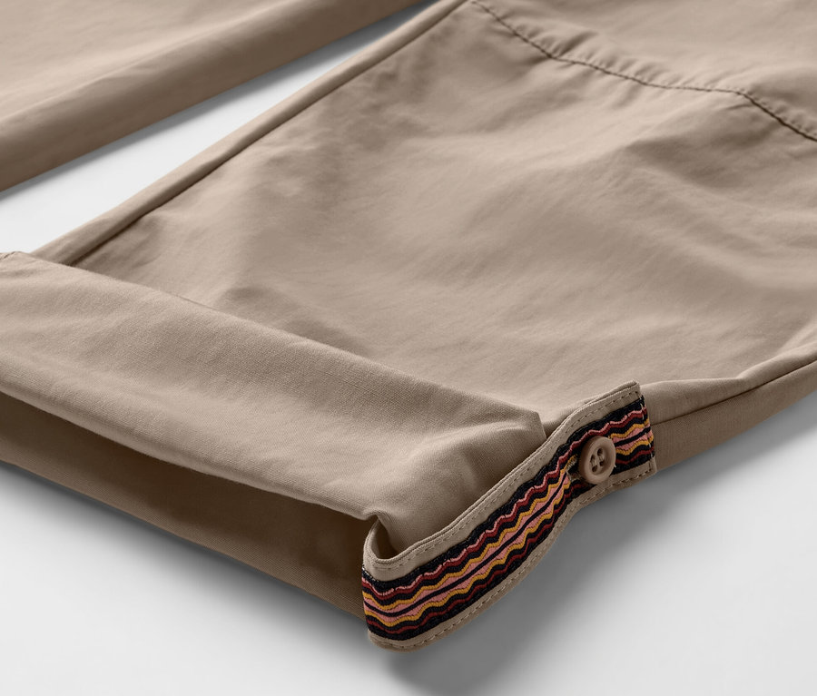 Paçaları kıvrılmış, düğmeli dekoratif şeritli bej rengi outdoor pantolonun yakın çekim görüntüsü. Pantolon sivrisinek korumalıdır.