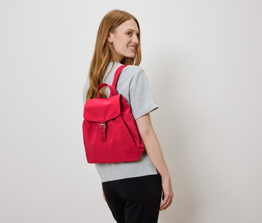 Sırtında kırmızı sırt çantası olan kadın sola bakıyor.