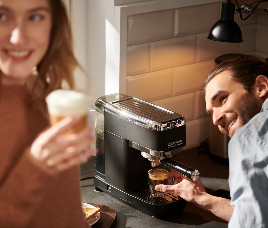 Adam, siyah »Lapressa« Portafiltre Makinesi ile espresso hazırlıyor, kadın latte tutuyor.