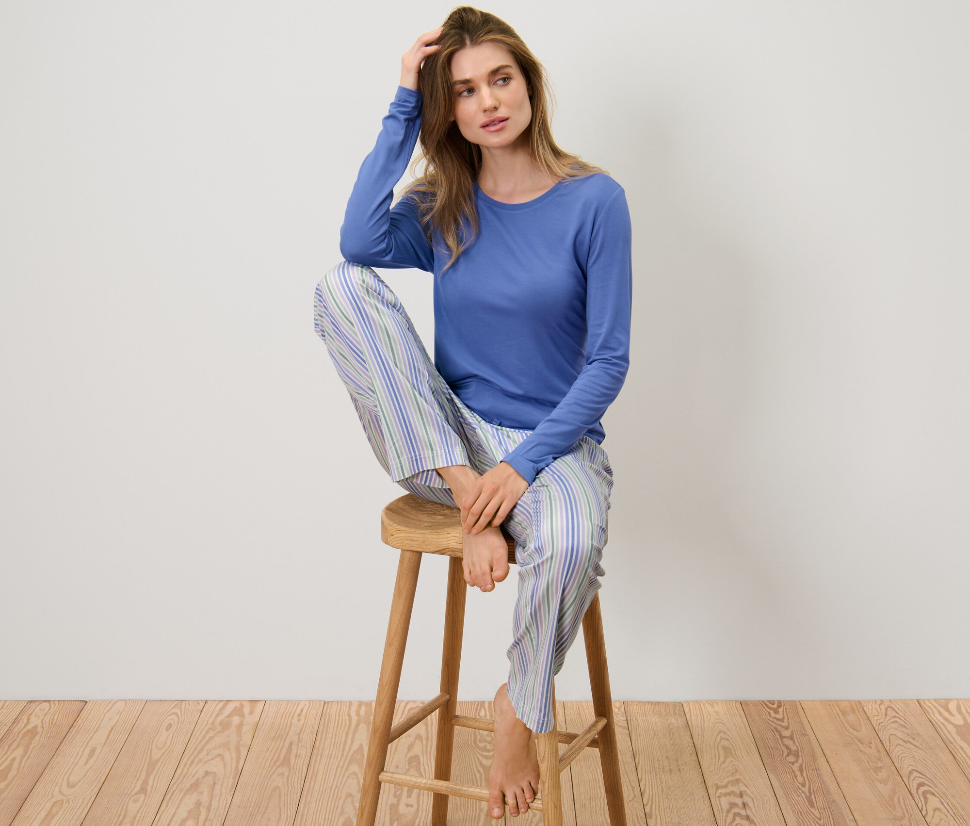 Kadın dokuma altlı pijamayla taburede oturuyor.