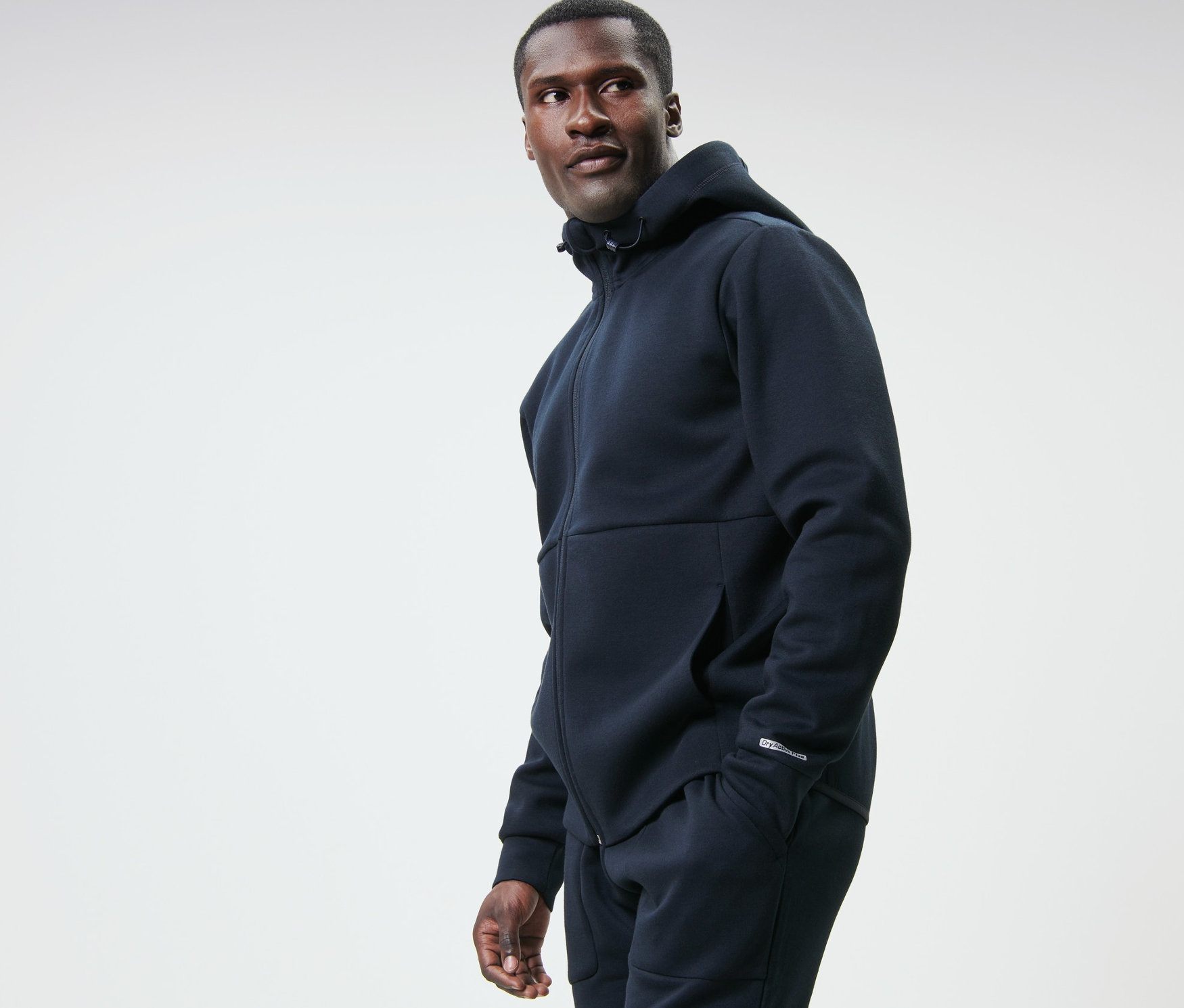 Lacivert fonksiyonel sweatshirt ceketli bir adam sola bakıyor.