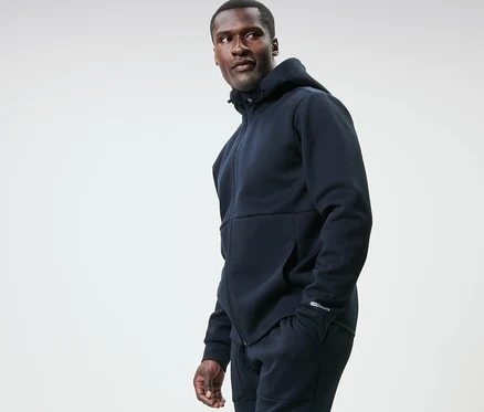 Lacivert fonksiyonel sweatshirt ceketli bir adam sola bakıyor.