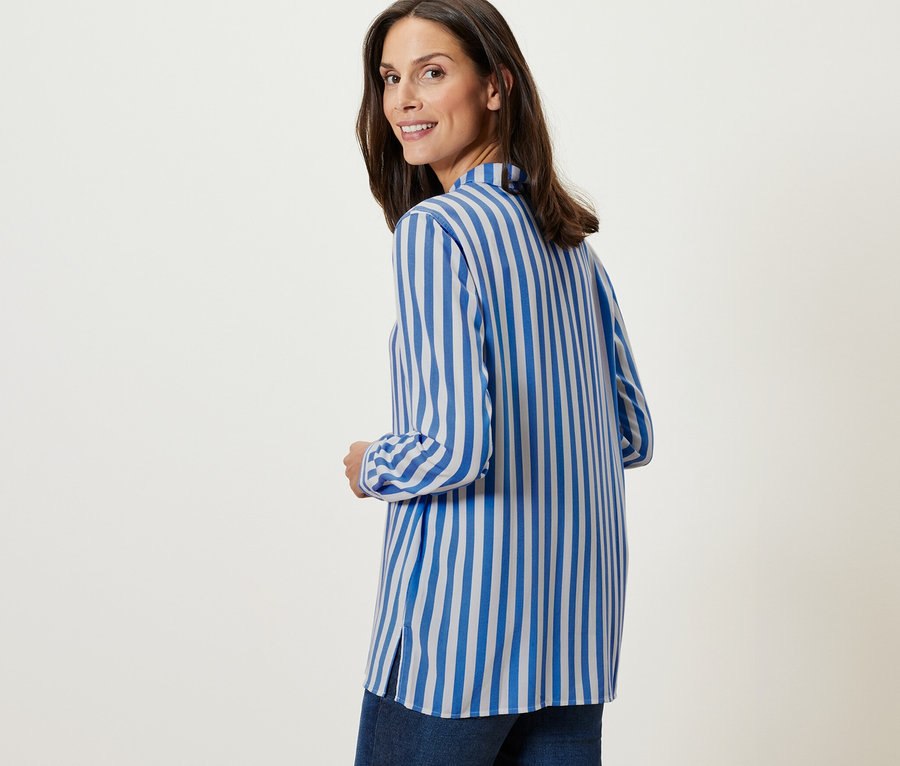 Omuzunun üzerinden bakan bir kadın Çizgili Bluz giyiyor.