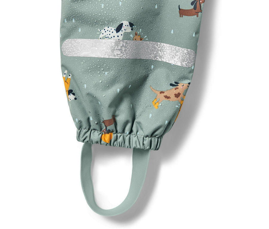 Köpek deseni ve reflektörlü şeridi olan, su damlalarıyla kaplı çocuk termal yağmur pantolonunun detayı.