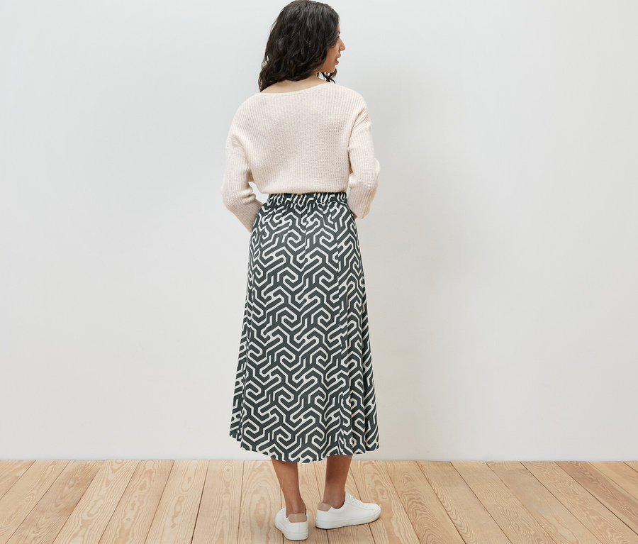 Arkadan görünen, desenli bir midi etek giyen kadın.