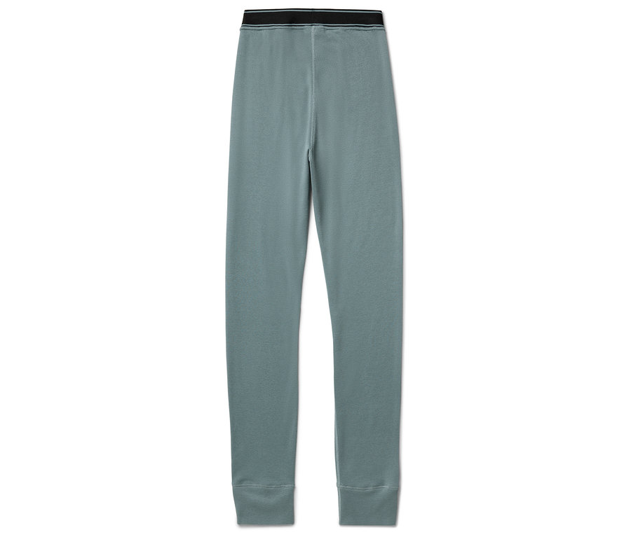 Mavi tayt siyah bantlı beyaz bir arka plan üzerinde duruyor.