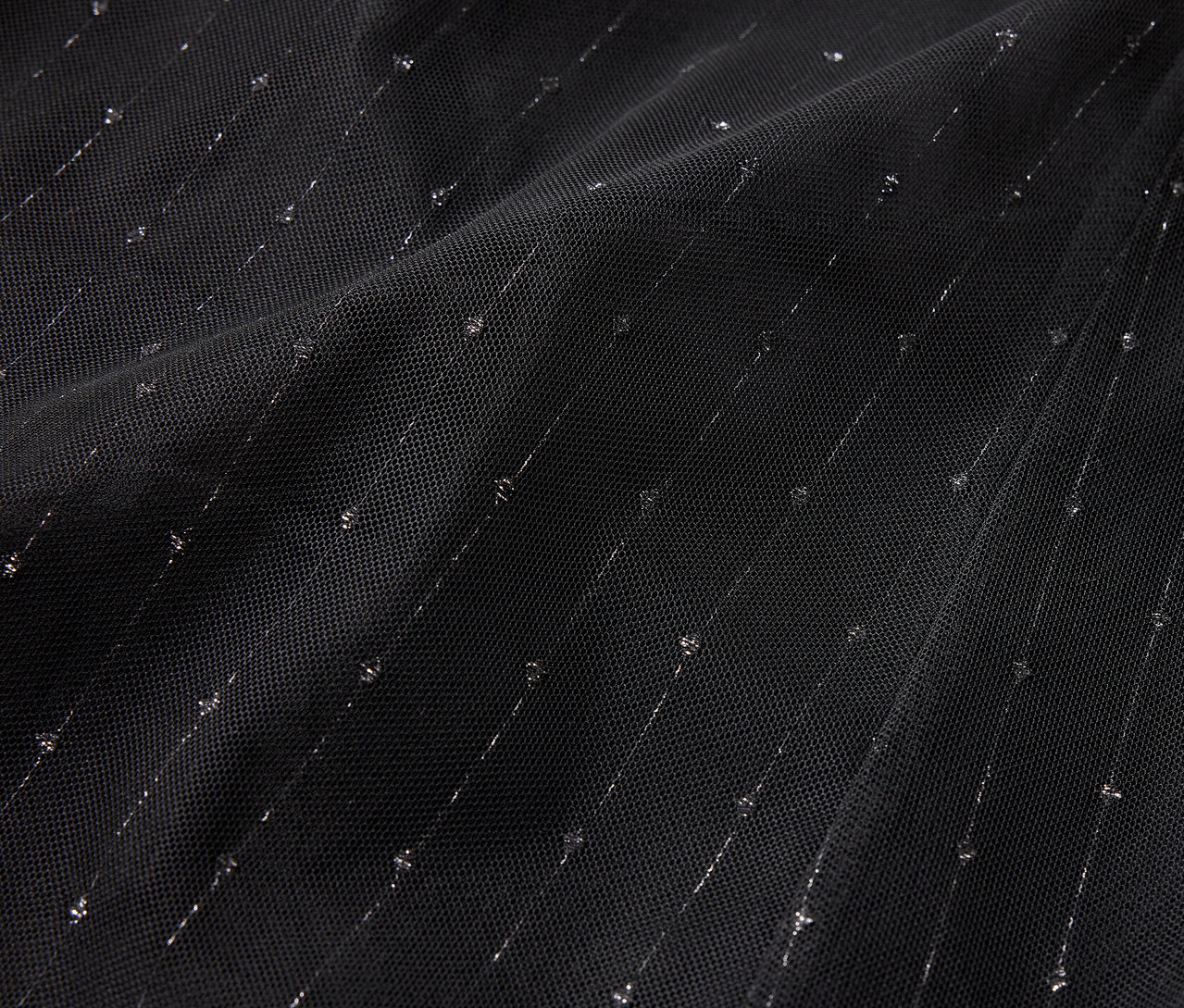 Siyah kumaşın diyagonal gümüş şeritler ve noktalarla yakın çekim görüntüsü.