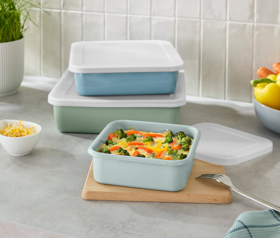 Beyaz kapaklı istiflenmiş yeşil ve mavi dikdörtgen kaplar ve küçük bir kase rendelenmiş peynir.