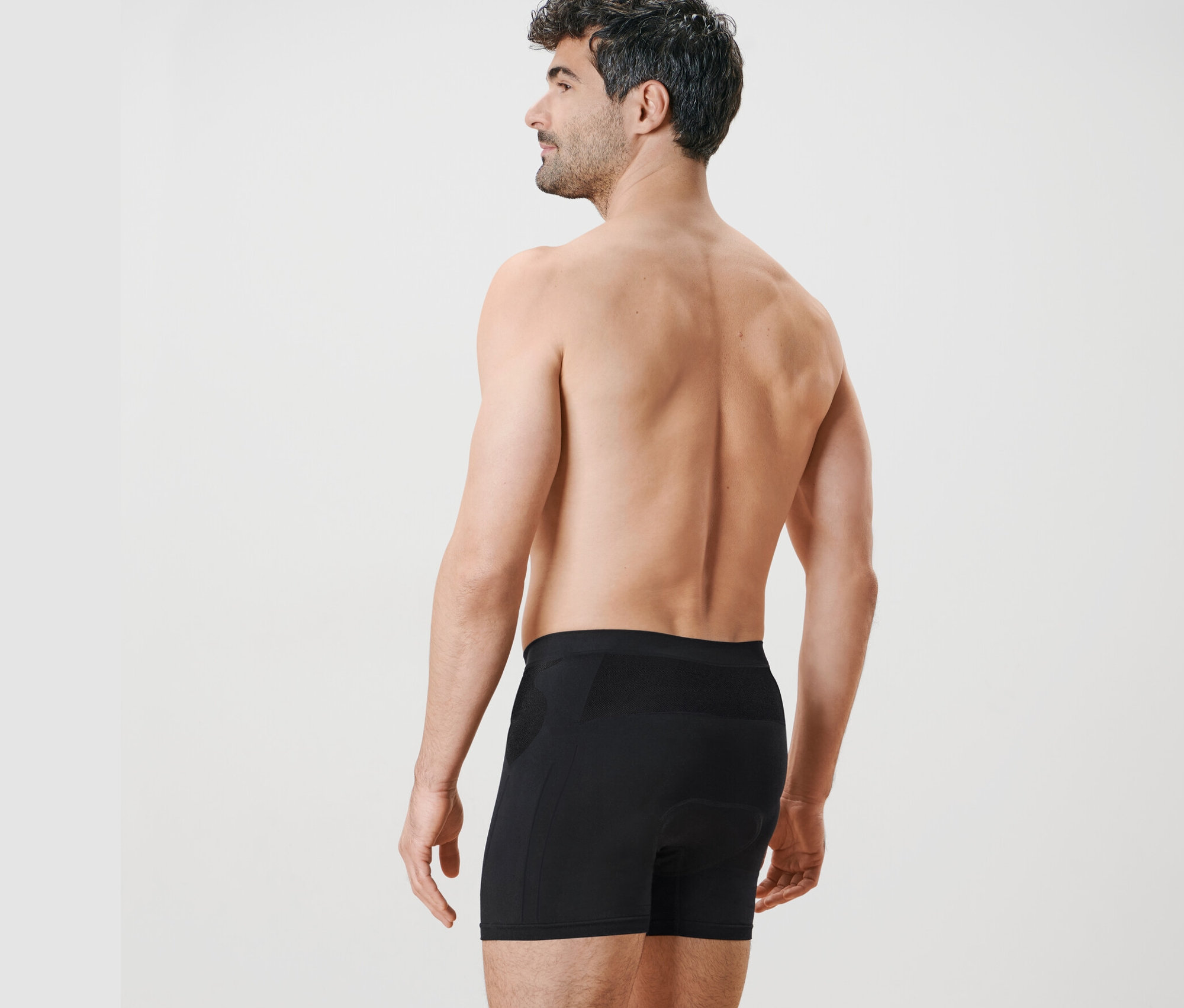 Arkadan görünen bir adam siyah bisiklet külodu giyiyor.