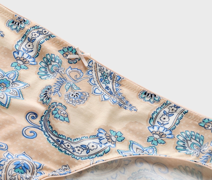 Mavi paisley desenli ve kurdeleli bej renk külodun yakın çekimi.