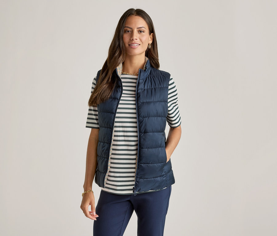 Yeşil çizgili yarım kollu tişörtün üzerine lacivert yelek giyen kadın.