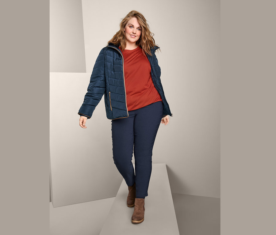 Podyumda yürüyen bir kadın; üzerinde Steppjacke, Kurzarmshirt mit Stickerei ve Bengalin-Hose var.