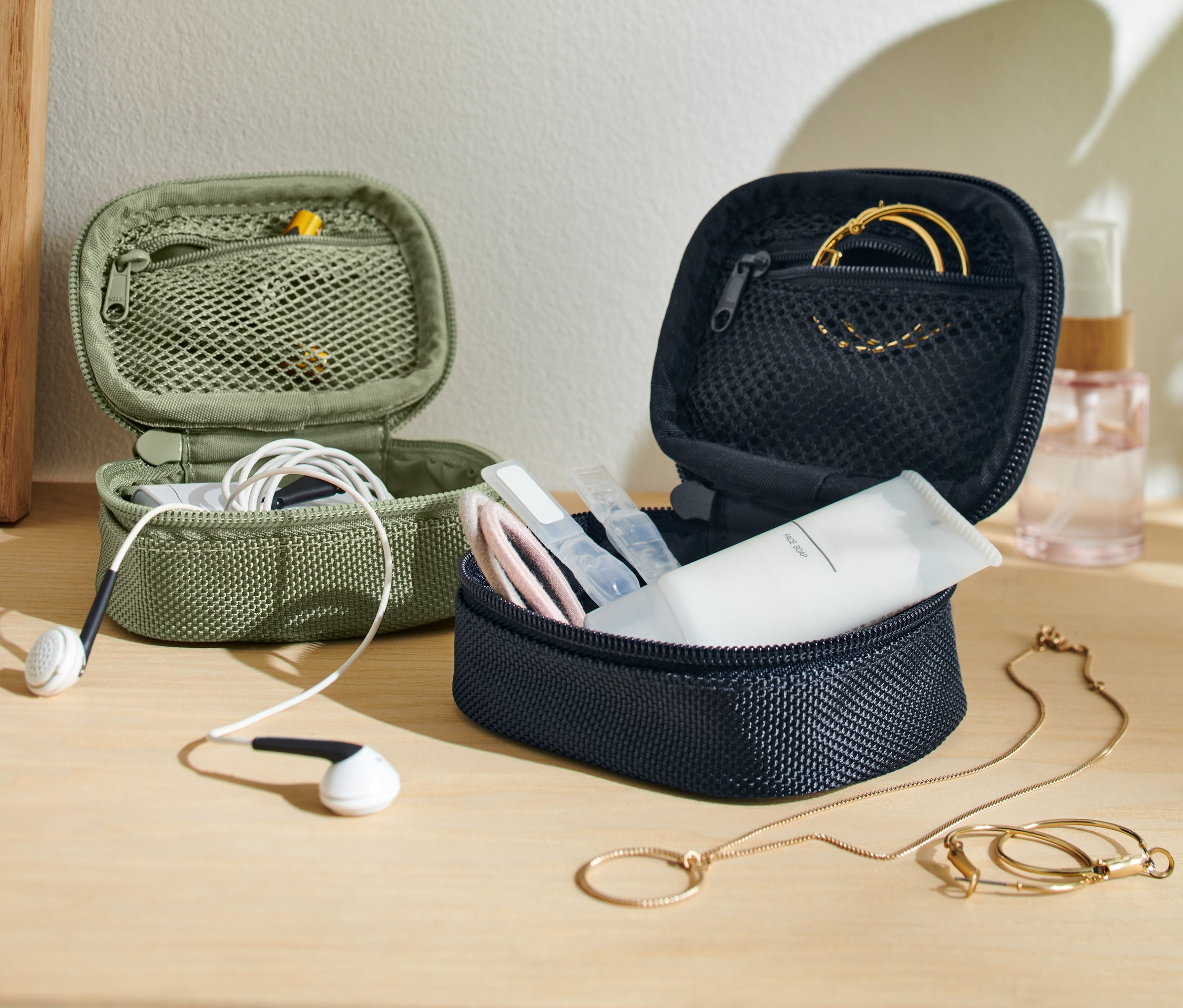 İki adet mini seyahat düzenleme çantası, bir zeytin yeşili kulaklıklı, bir lacivert kozmetik ve mücevherli.