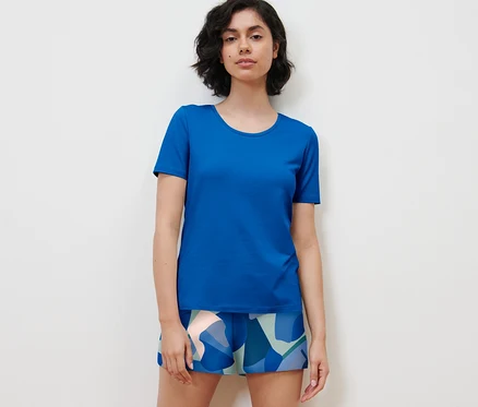 Kadın şortlu pijama takımı giyiyor.
