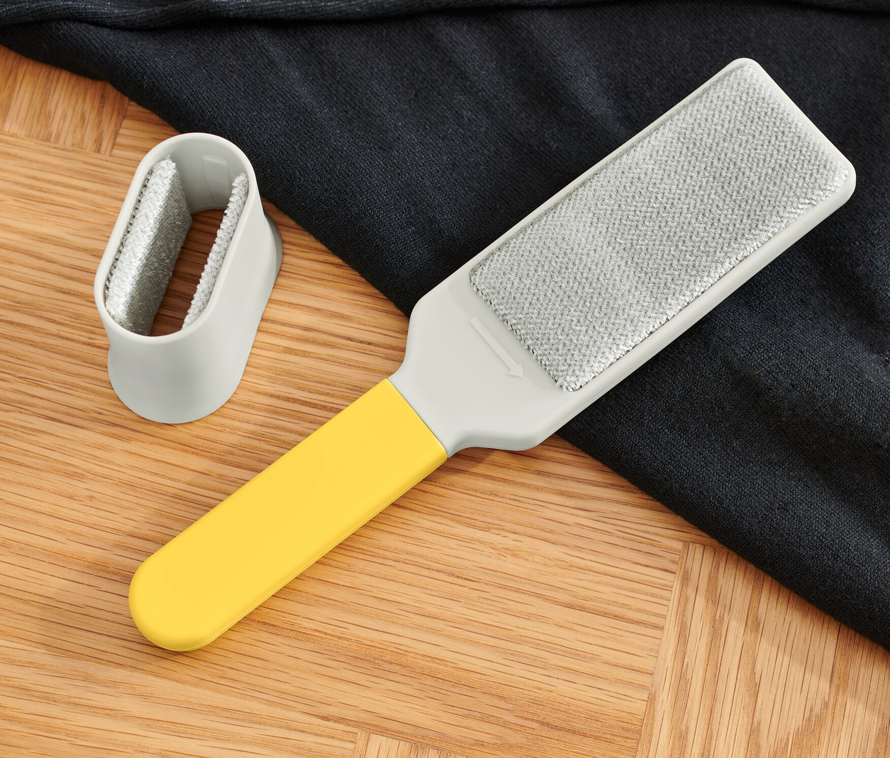 Ahşap bir zeminde bir elbise fırçası ve koyu renkli bir kazak duruyor.