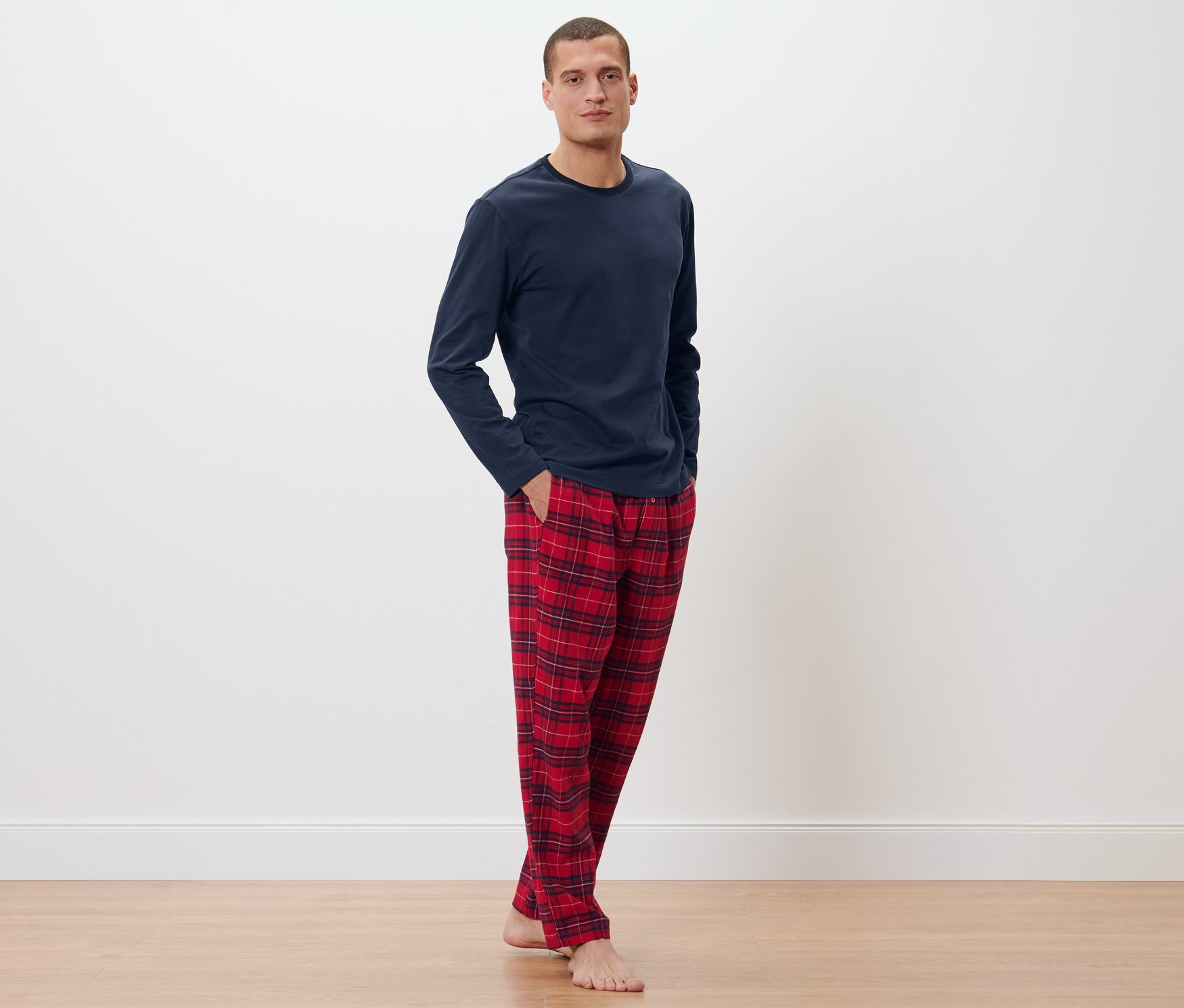 Lacivert pijama üstü ve ekose desenli pazen pantolonla poz veren adam.