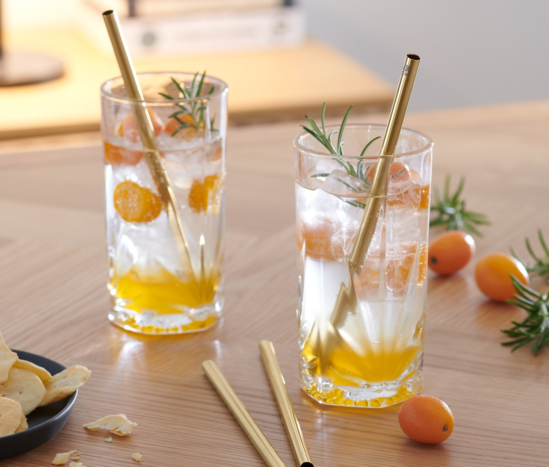 Ahşap bir masa üzerinde meyve parçaları ve 4 adet Metal Pipet içeren iki içecek.