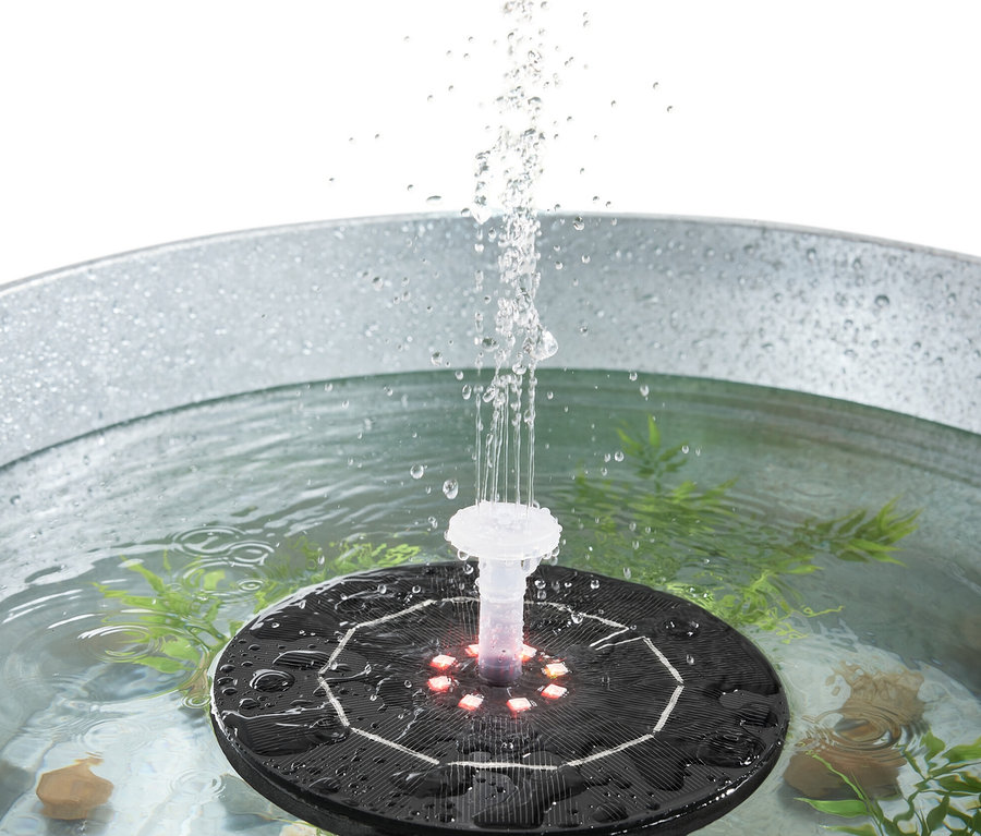 Işıklı yüzen güneş enerjili fıskiye metal bir kovada su püskürtüyor.