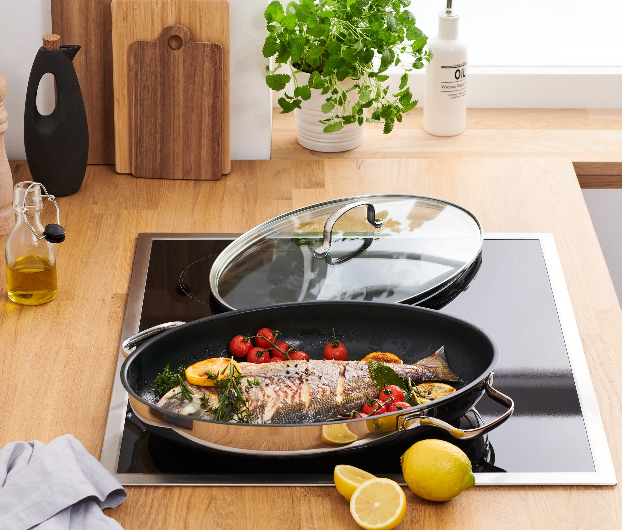 İndüksiyonlu ocakta balık, çeri domates ve limon bulunan paslanmaz çelik servis ve balık tavası bulunmaktadır.