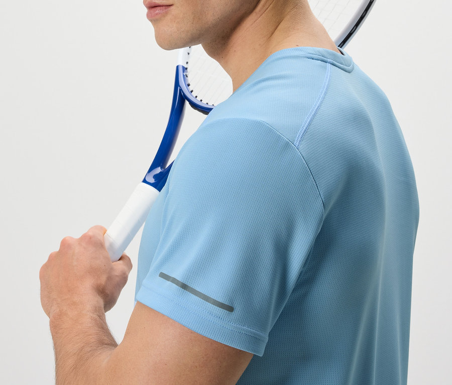 Omzunda tenis raketi olan bir adam açık mavi fonksiyonel tişört giyiyor.