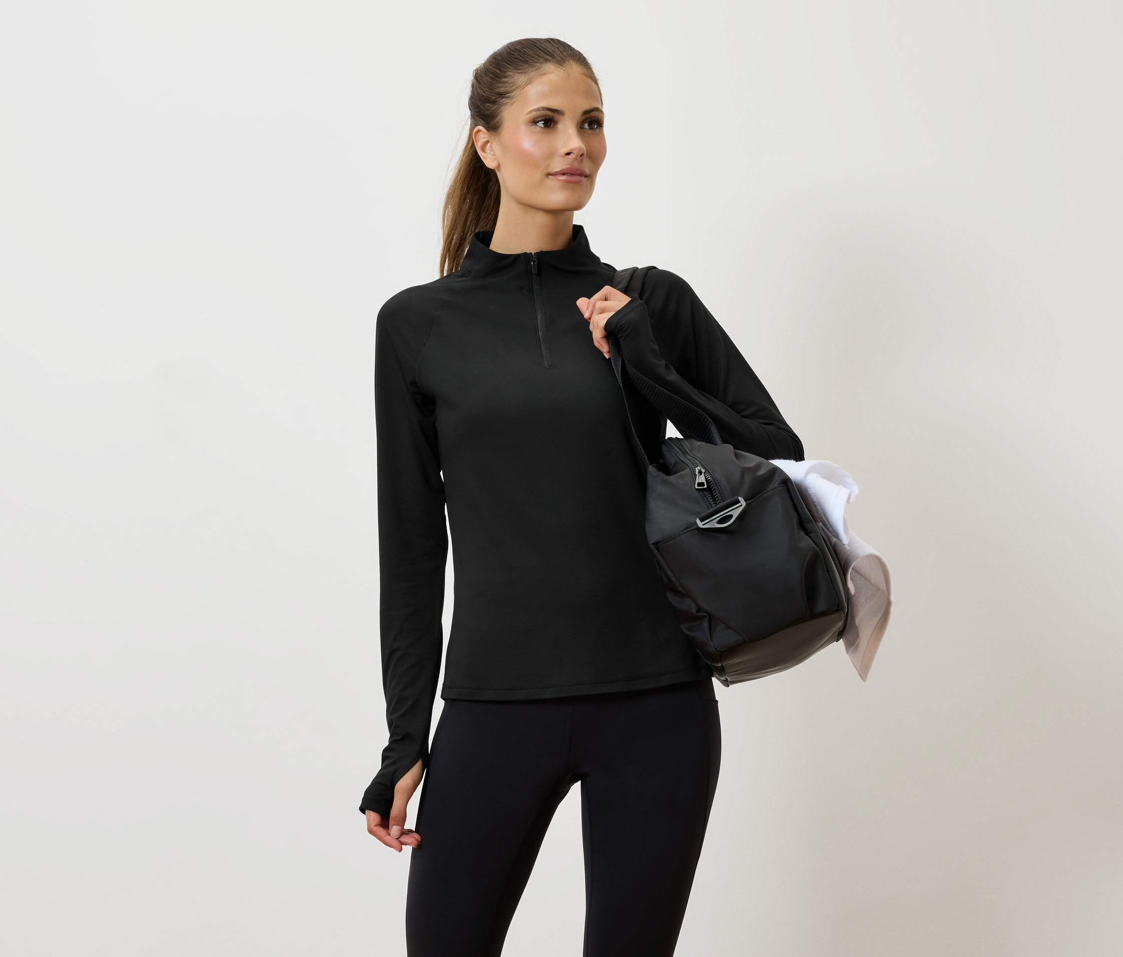 Omuzunda çantası olan siyah spor giyimli kadın.