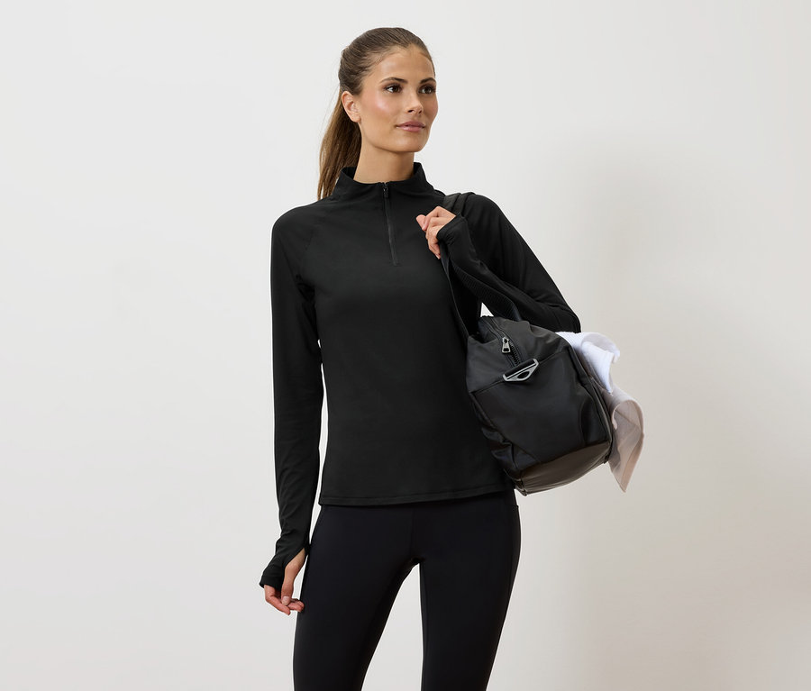 Omuzunda çantası olan siyah spor giyimli kadın.