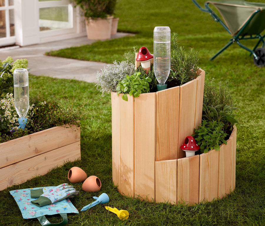 Çim üzerinde, otlar ve sebzelerle dikilmiş ahşap bir yükseltilmiş tarh »Salyangoz« duruyor.