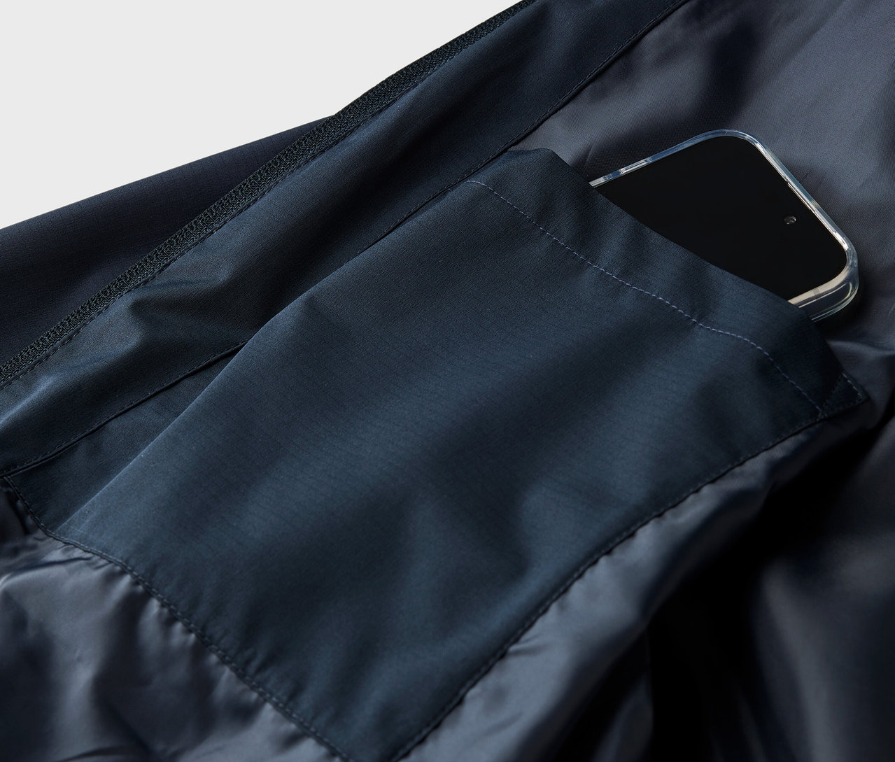 Cepinde akıllı telefon bulunan lacivert bir ceketin yakın çekim görüntüsü.