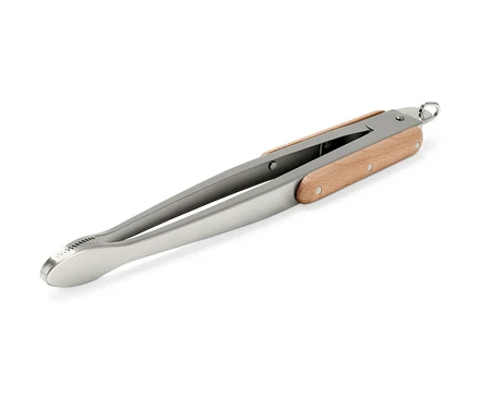 Ahşap saplı paslanmaz çelik barbekü maşası beyaz bir arka planda çapraz olarak duruyor.