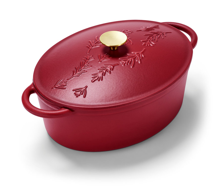 Kırmızı, oval demir döküm tencere, çam dalı desenli ve altın rengi kulplu.