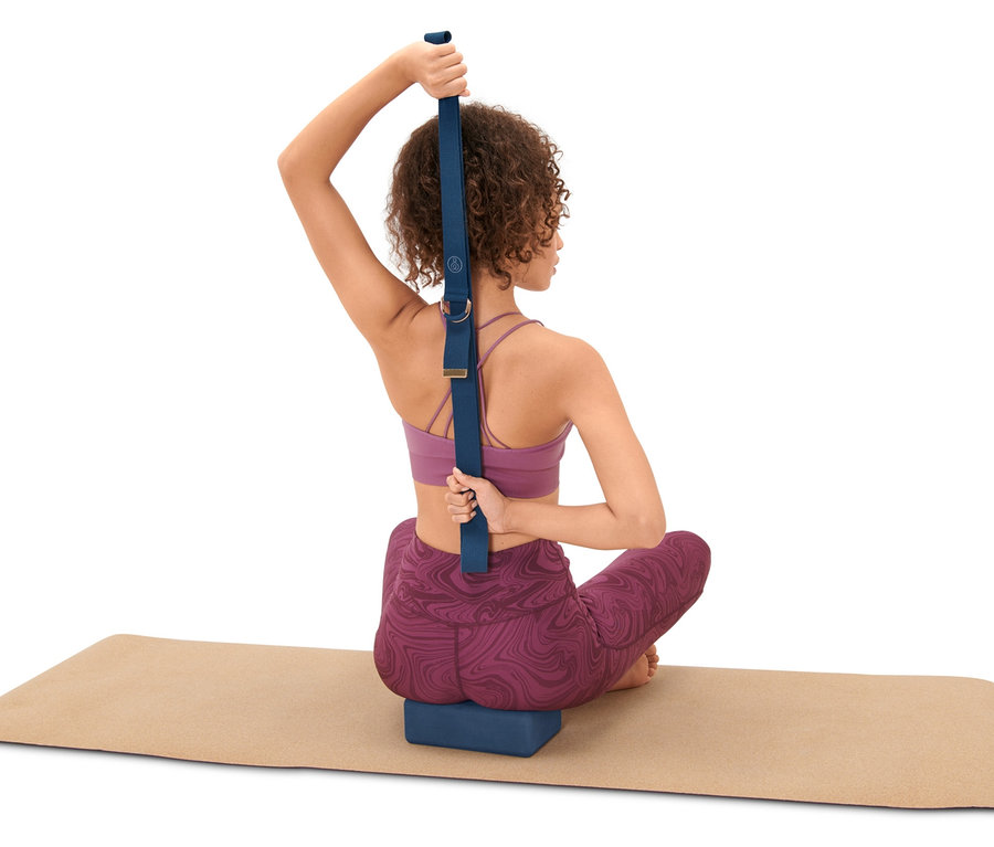 Kadın yoga matında oturuyor ve Yoga Seti kullanıyor: blok ve kemer
