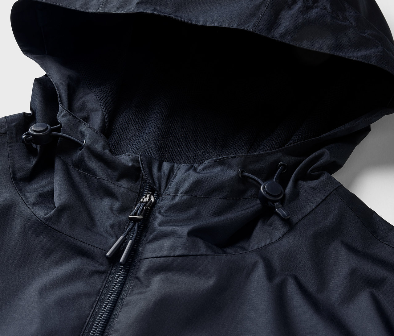 Kapüşonlu ve fermuarlı, lacivert bir yağmurluğun yakın çekimi.