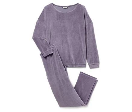 Uzun kollu ve pantolonlu mor renkli bir kadife pijama beyaz bir arka plan üzerinde duruyor.