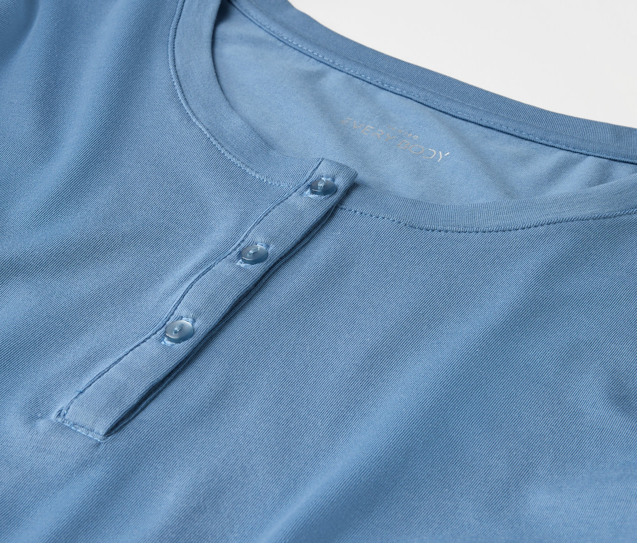 Düğmeli açık mavi bir tişörtün yakın çekimi.