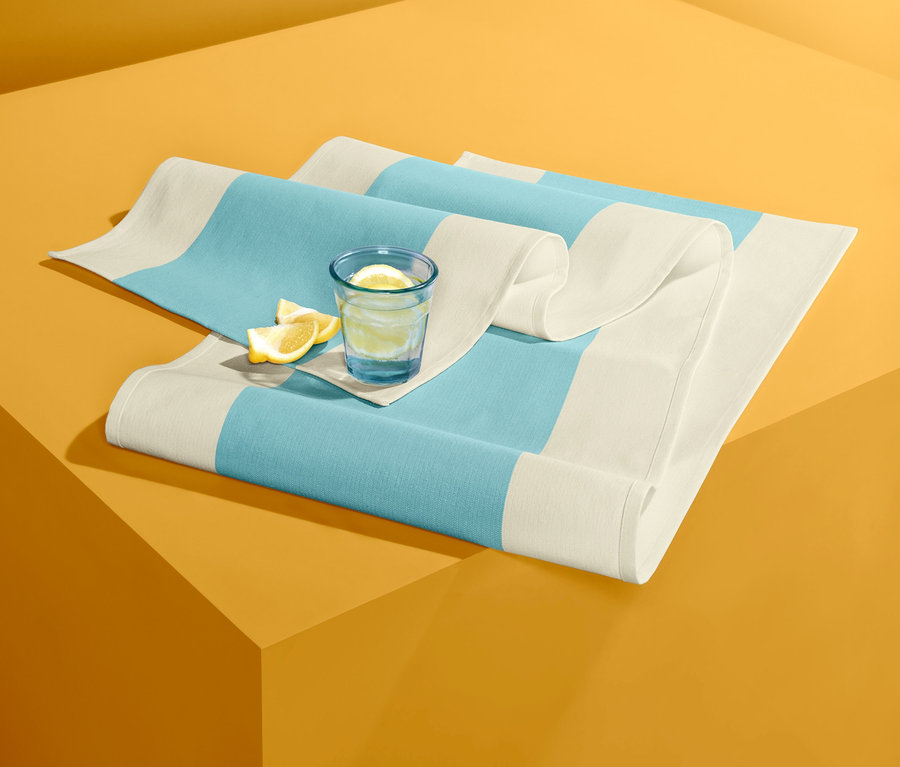 Mavi şeritli şerit örtü üzerinde limonlu su bardağı.