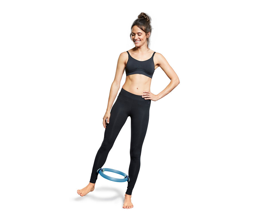 Kadın mavi Pilates halkasıyla egzersiz yapıyor.